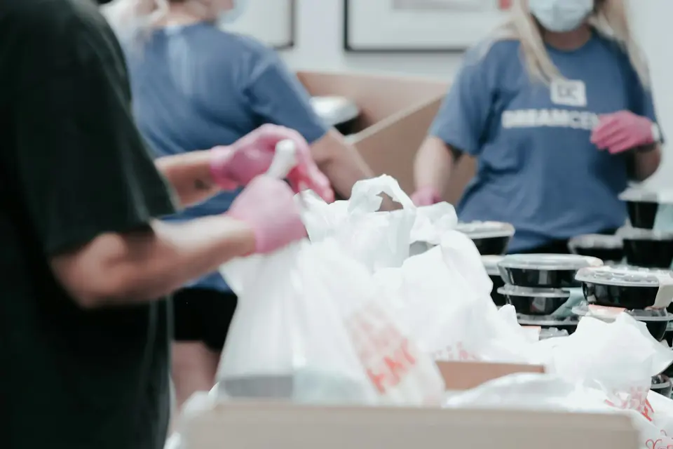 Volunteers in gloves packing groceries into bags