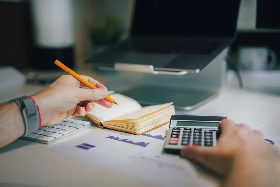 Person working with a calculator and a notebook
