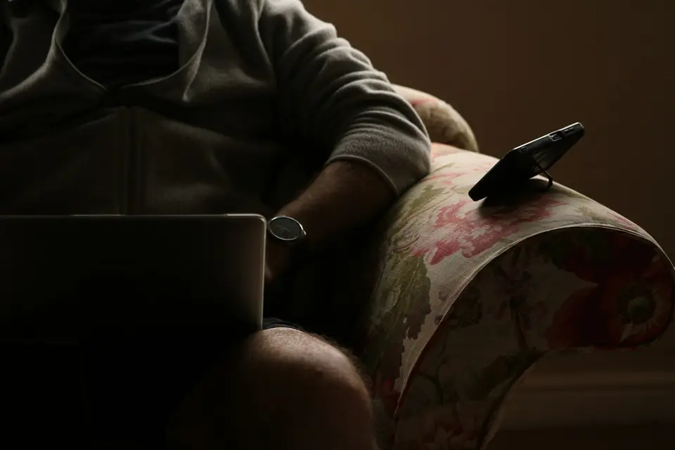 Person in an armchair with a laptop and phone