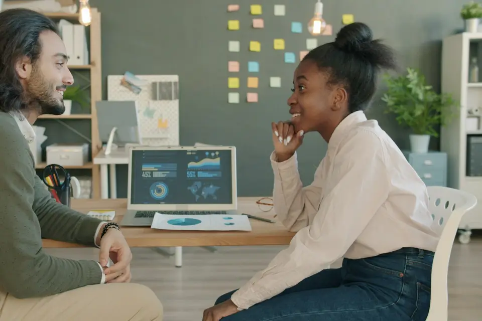 Two colleagues discussing work at a desk