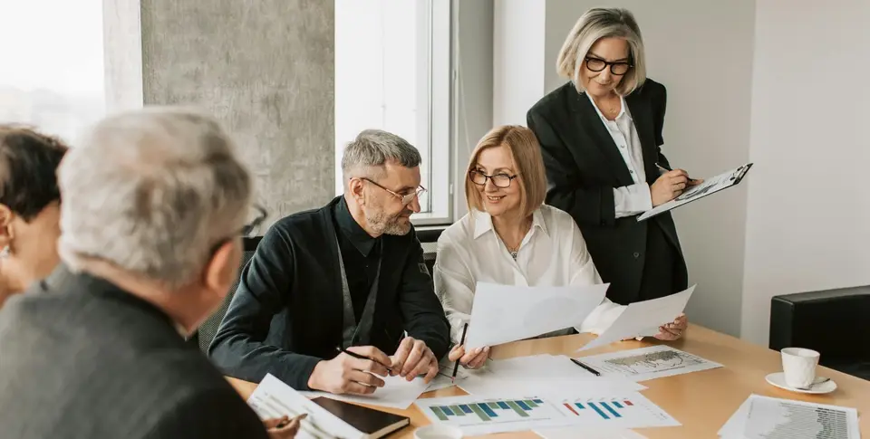 Mehrere Vorstandsmitglieder eines Vereins sitzen gemeinsam am Tisch und besprechen Dokumente und Finanzunterlagen.