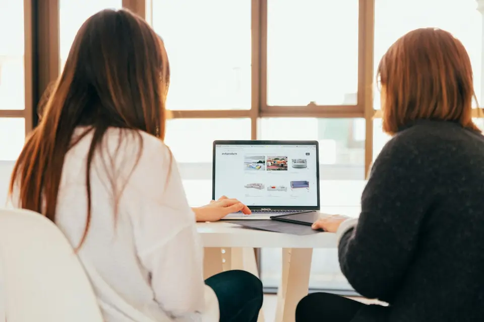 Two women talking while looking at a laptop