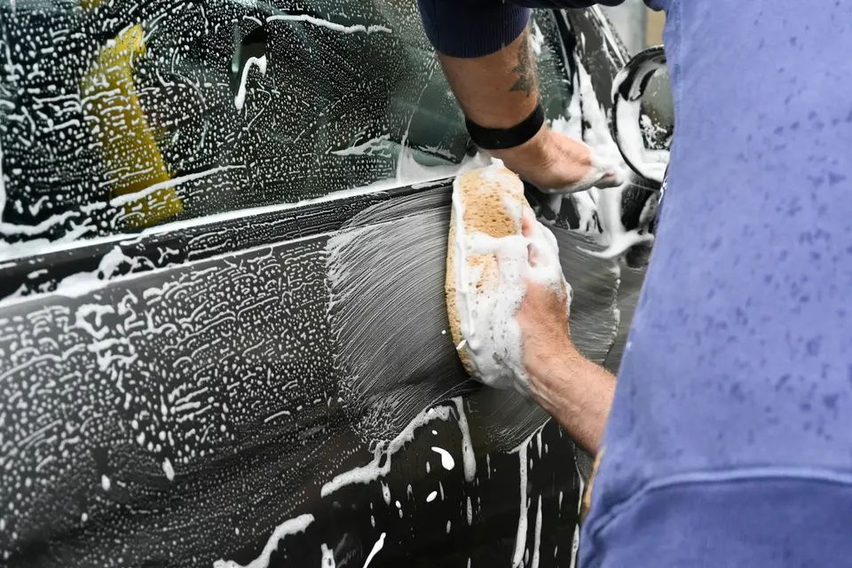 Man washing a car with a sponge