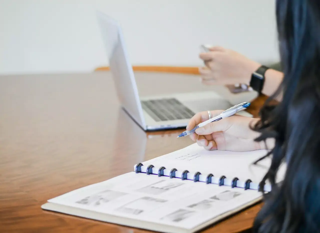 Laptop und Notizbuch, Kugelschreiber in der Hand