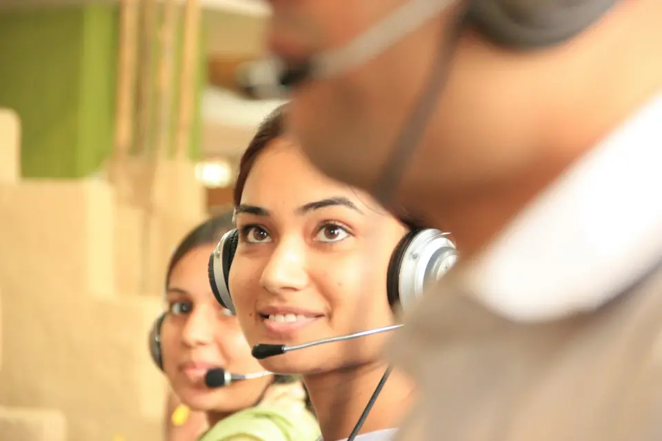 Two women with headsets working in a bright office
