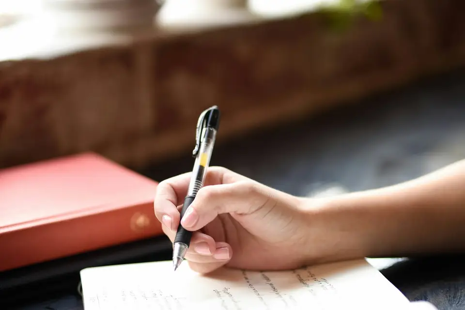 Person writing with a pen on a sheet of paper