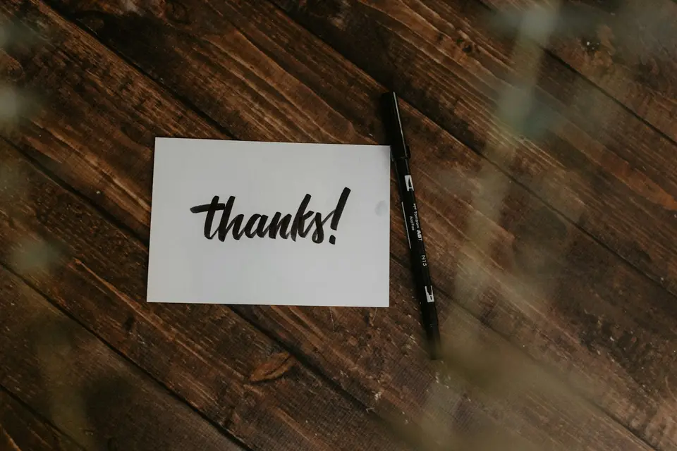 Handwritten thank-you note with a black pen on wood