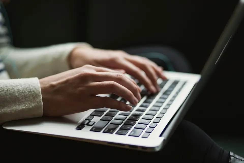Person using a laptop at a wooden desk