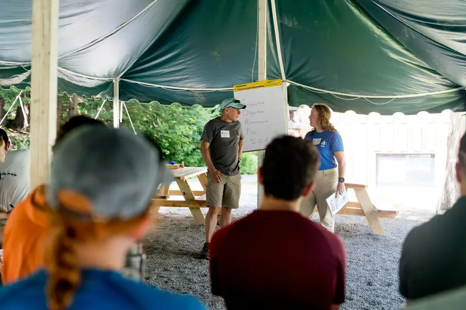 People gathered under a tent for a presentation
