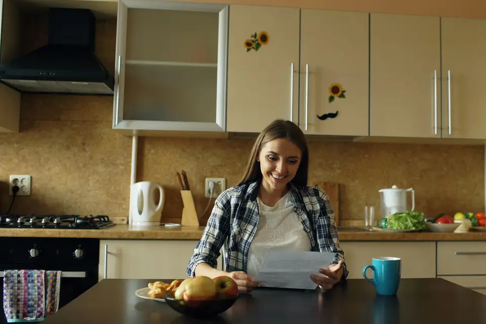 Woman reading a document at a kitchen table with coffee