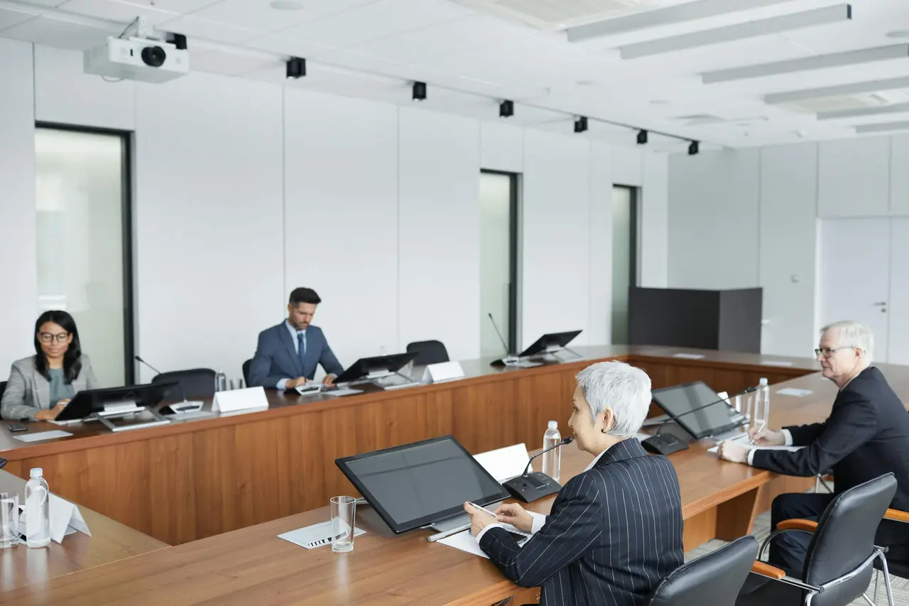 Mehrere Personen sitzen an einem Konferenztisch und nehmen an einer formellen Gremiensitzung teil – symbolisch für eine Verbandsversammlung