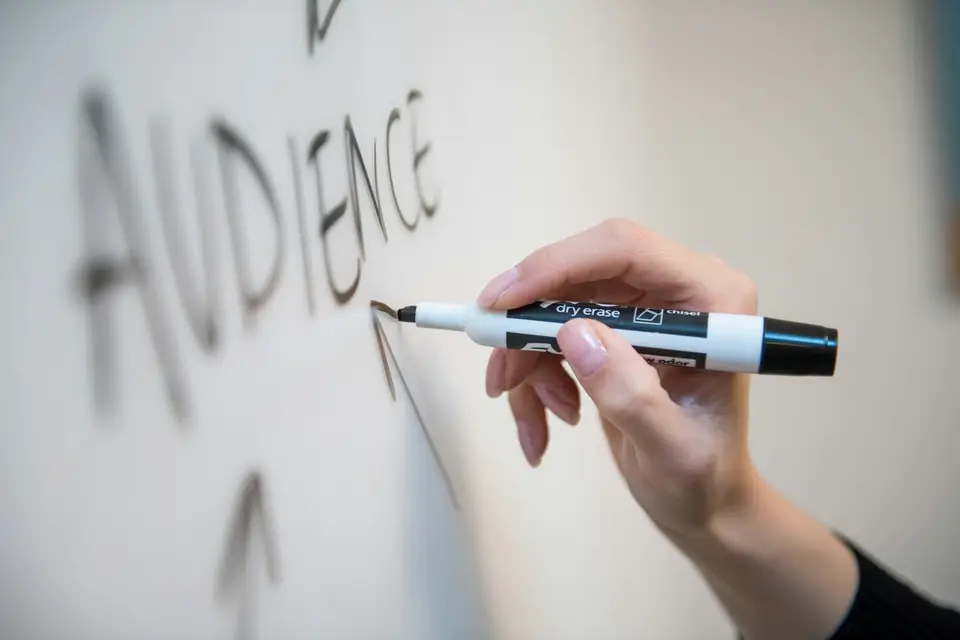 Hand holding a marker in front of a whiteboard