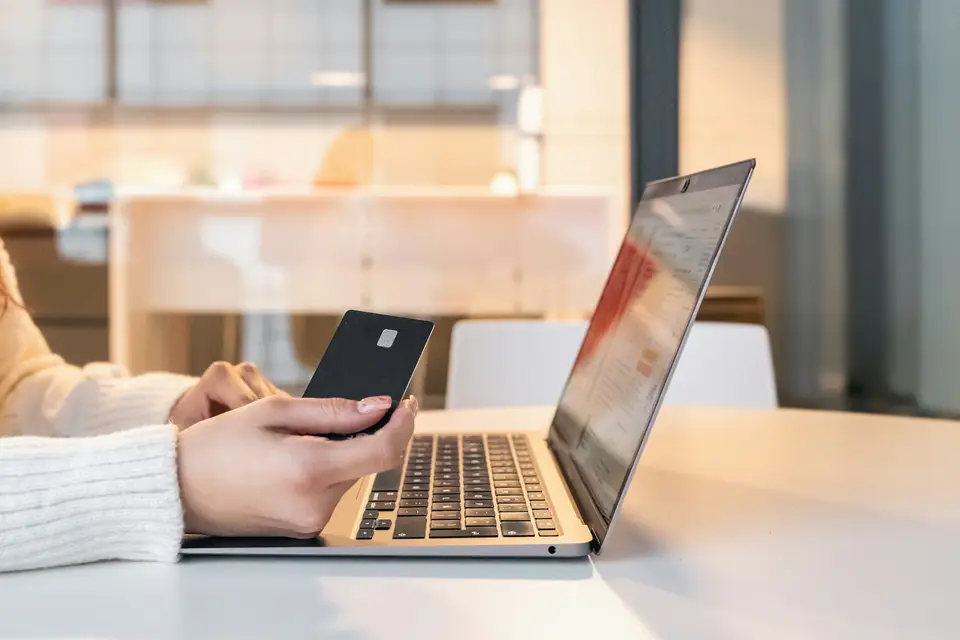 Woman at a laptop holding a phone