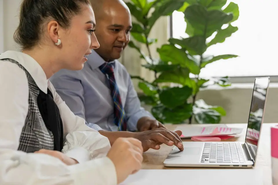 personen sitzen am tisch und schauen auf den laptop