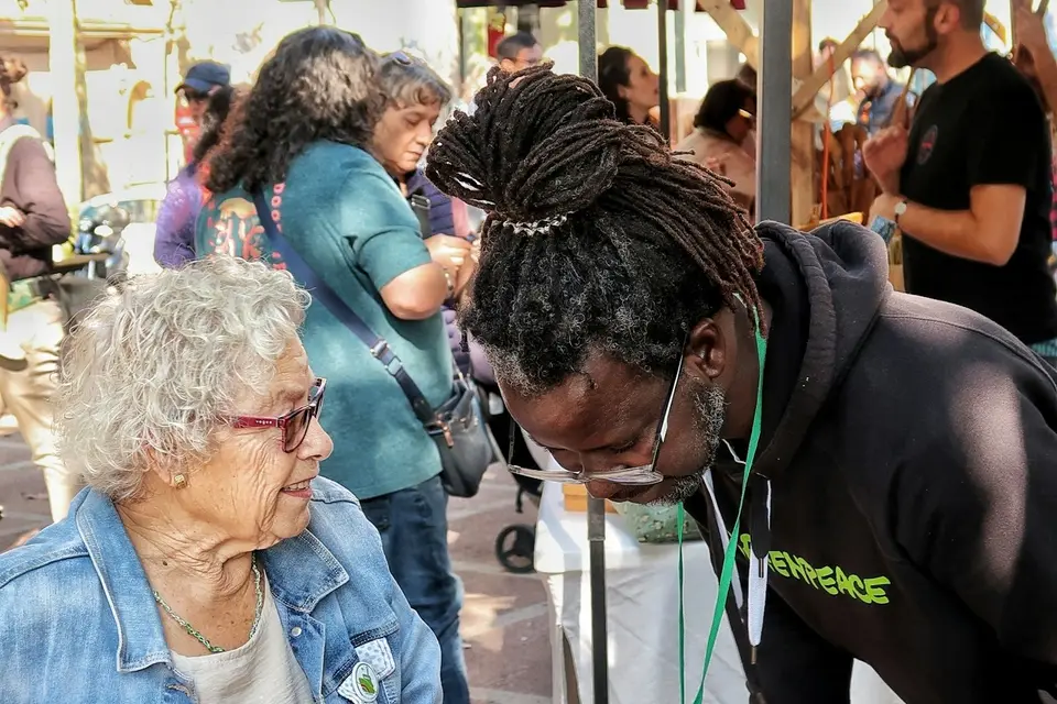 Older woman in a wheelchair talking with a man outdoors