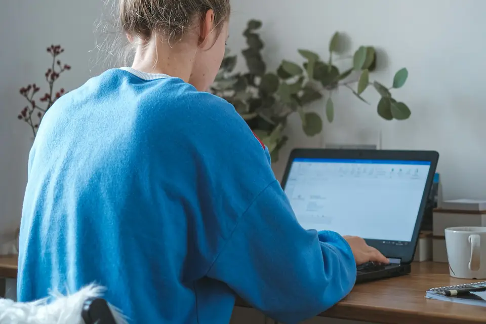 Woman in a blue sweater working at a laptop