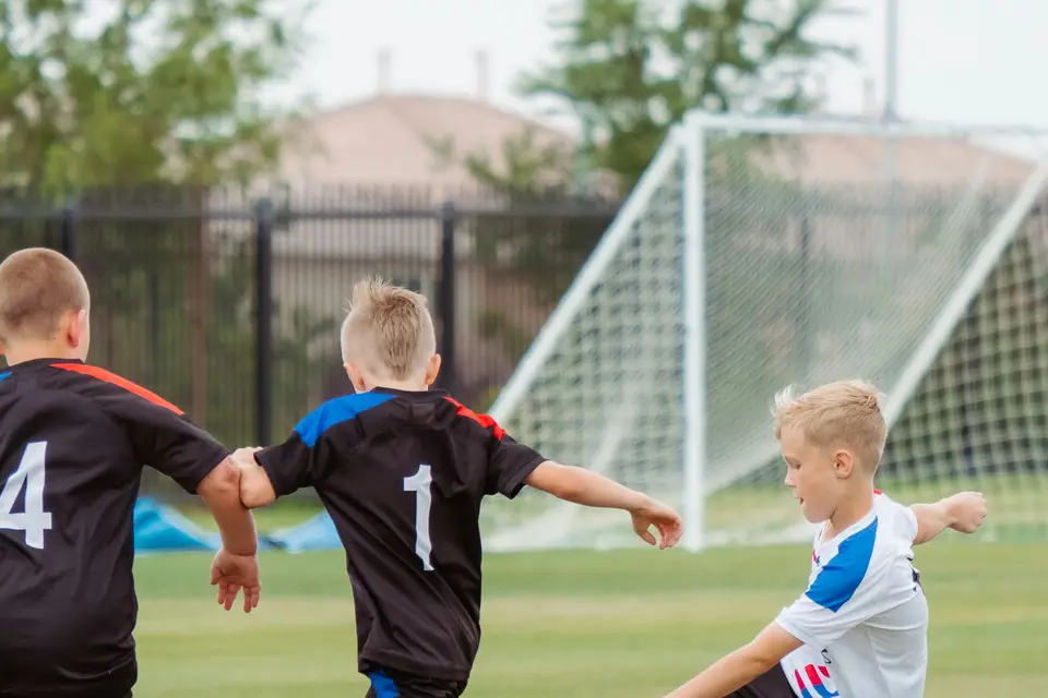 Drei Jungen kämpfen beim Fußballtraining vor dem Tor um den Ball