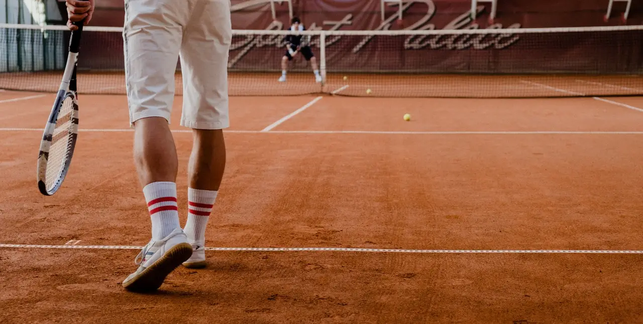 Ein Mann steht auf einem Tennis-Sandplatz