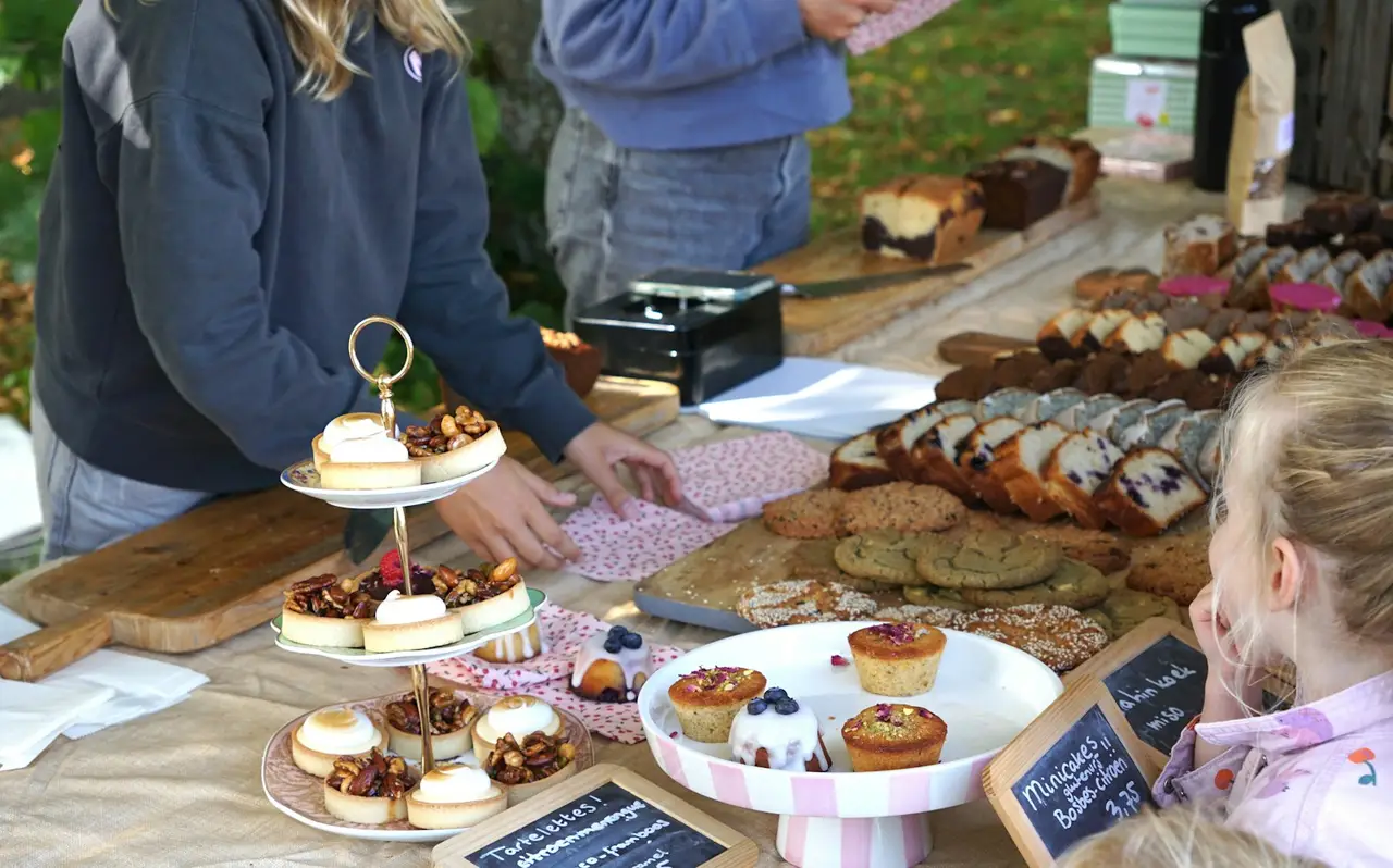 Volunteers and children at a bake sale table.