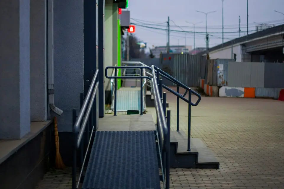 Barrierefreie Rampe mit Handläufen neben einer Treppe am Eingang