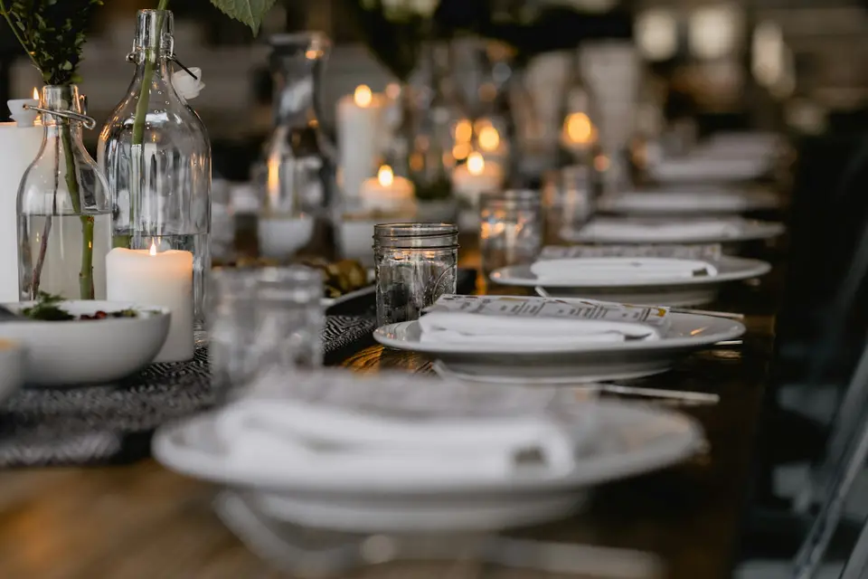 Long dinner table set with plates, candles and glasses