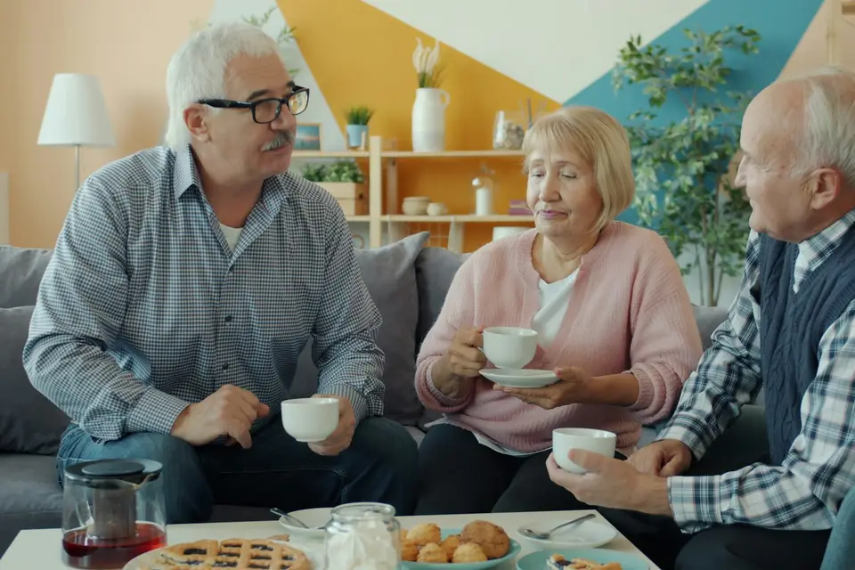 Three older adults talking over coffee at home