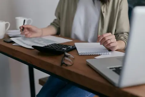 Person sitzt am Tisch und hält einen Stift in der Hand.