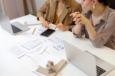 Unterlagen liegen auf Tisch Laptop Taschenrechner Frauen sitzen