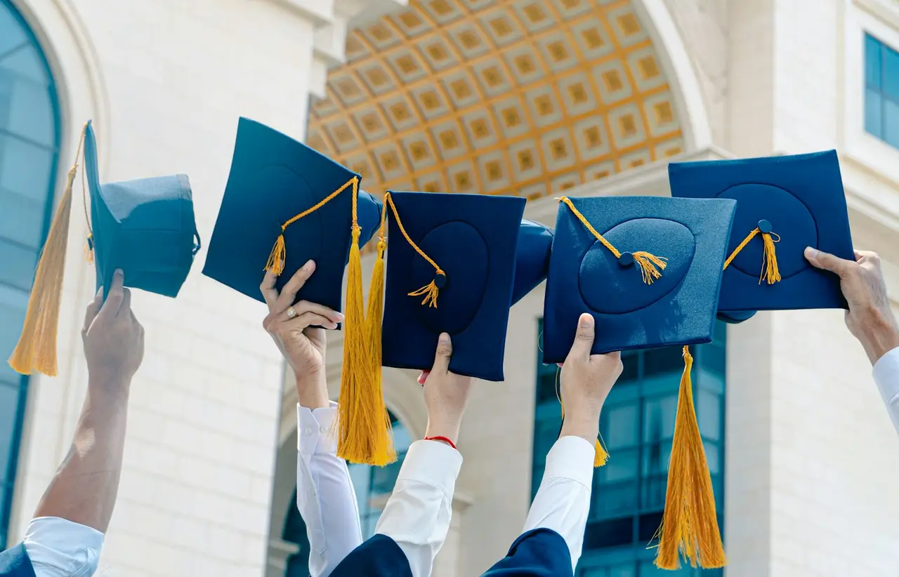 Graduates raising their caps in celebration.
