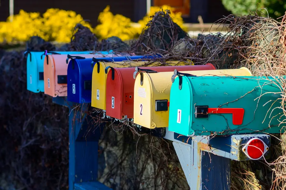 Row of colorful mailboxes next to a bush
