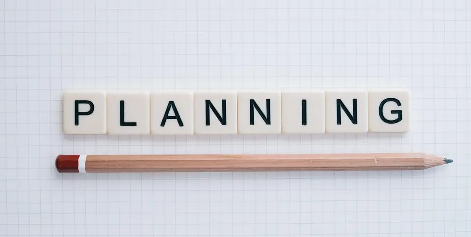 Schriftzug "Planning" mit Stift auf einem karierten Papier