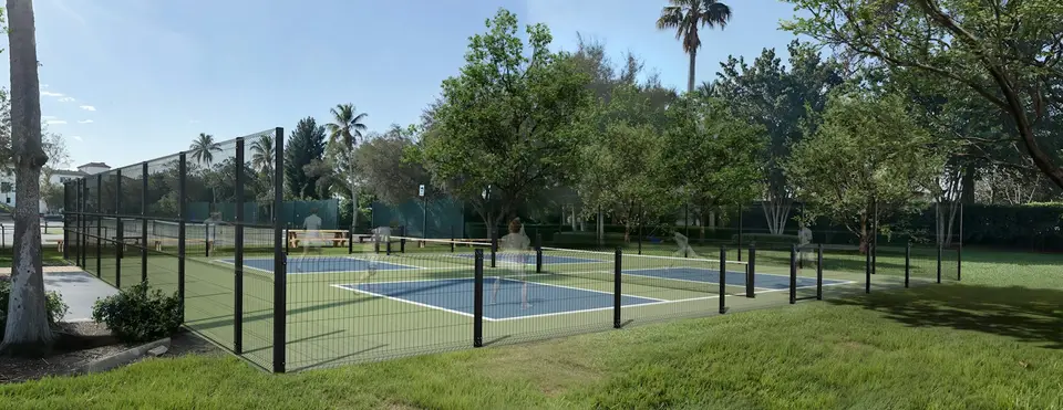 Fenced community sports courts surrounded by trees.
