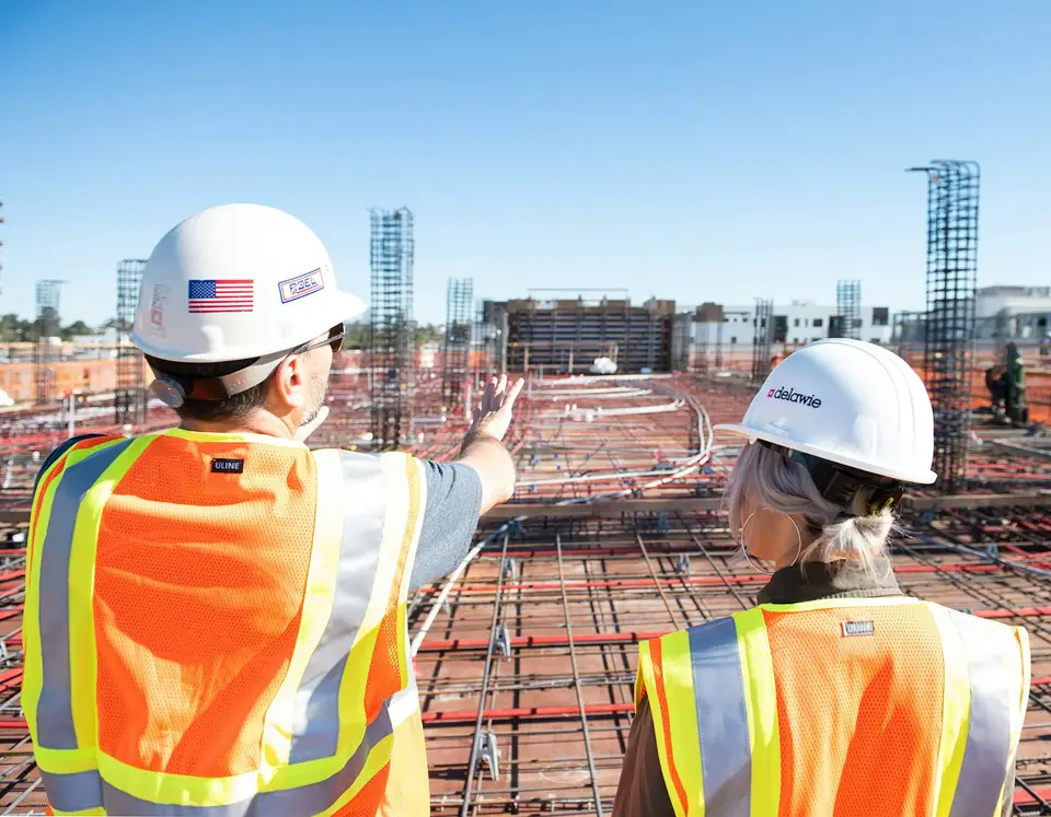 Construction managers in hard hats discussing a building site.