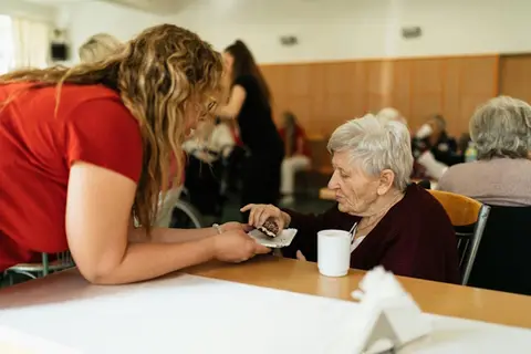 Frau beugt sich zu einer älteren Dame