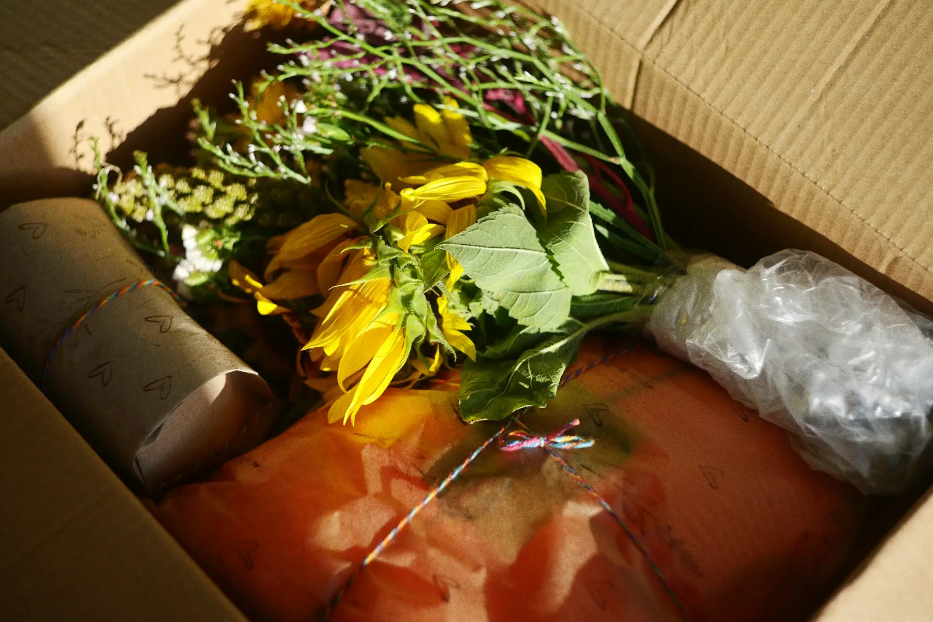 Ein Karton mit einem Strauß Sonnenblumen und liebevoll verpackten Geschenken