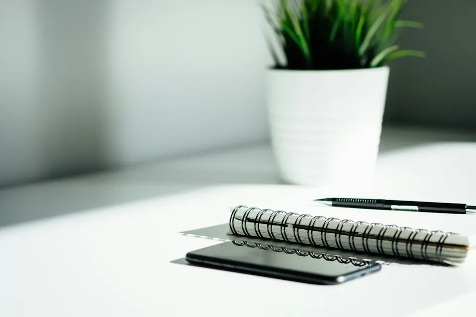 Stift, Notizbuch und Smartphone auf einem Tisch