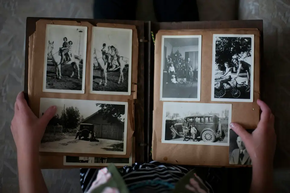 Person opening a photo album with black-and-white photos