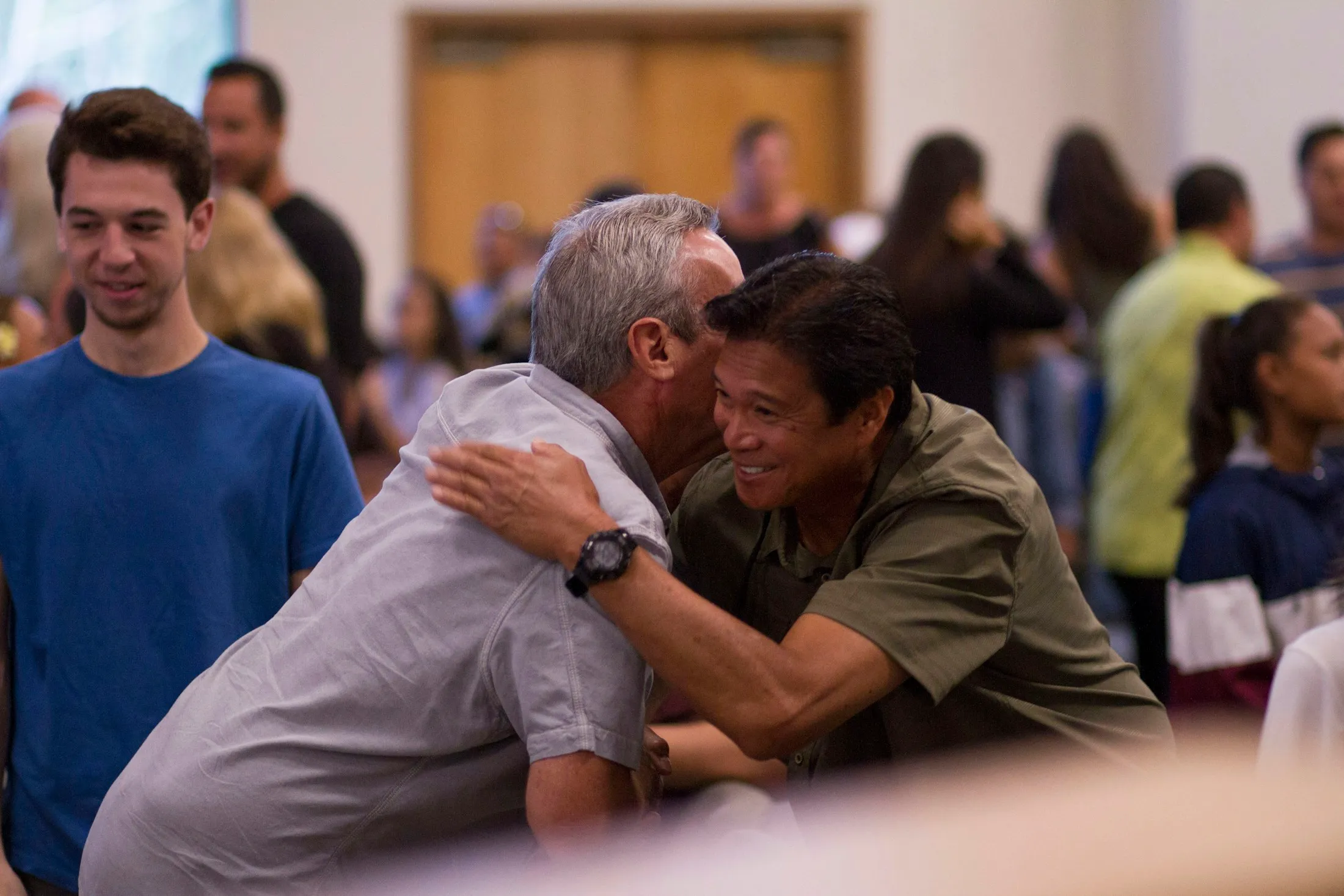 People embracing and greeting each other during a church gathering.