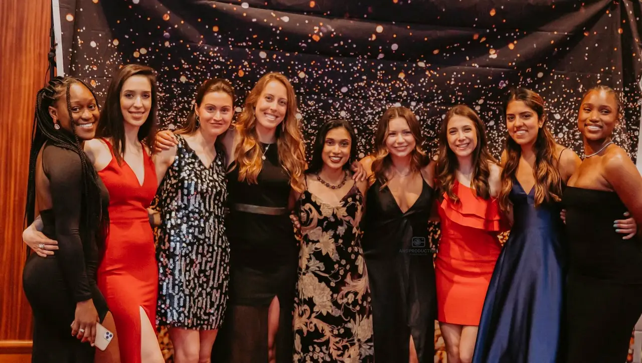 Guests in evening wear posing together at a gala.