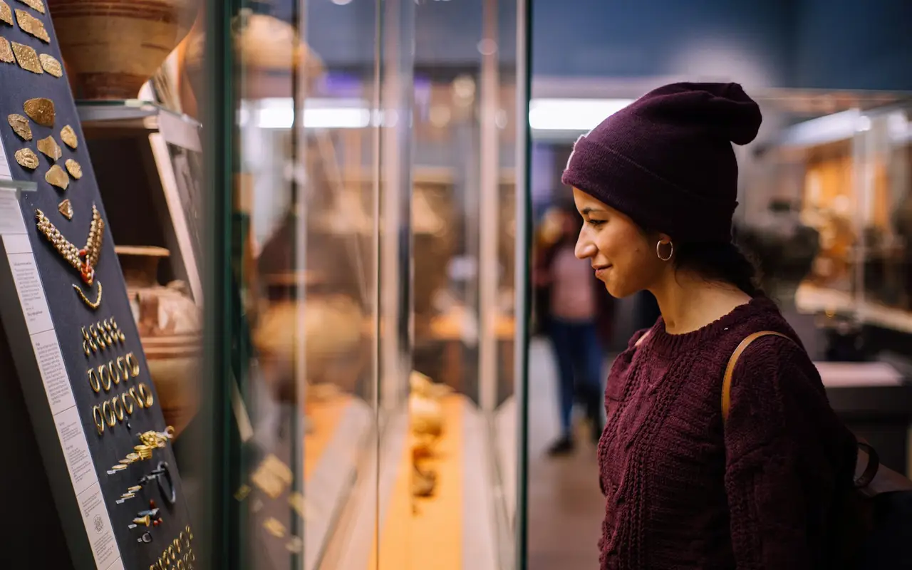 A visitor looking closely at objects in a museum display case.