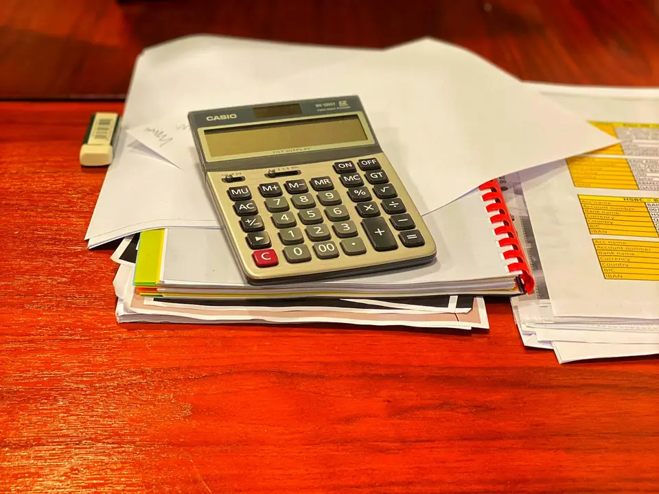A calculator and paperwork on a desk.