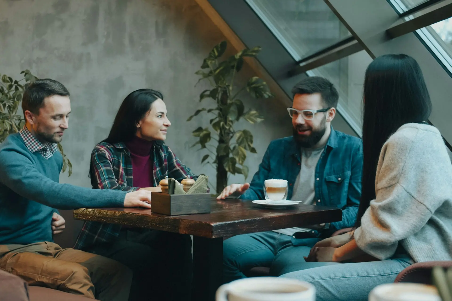 Vier Personen besprechen sich an einem Holztisch in einem Café