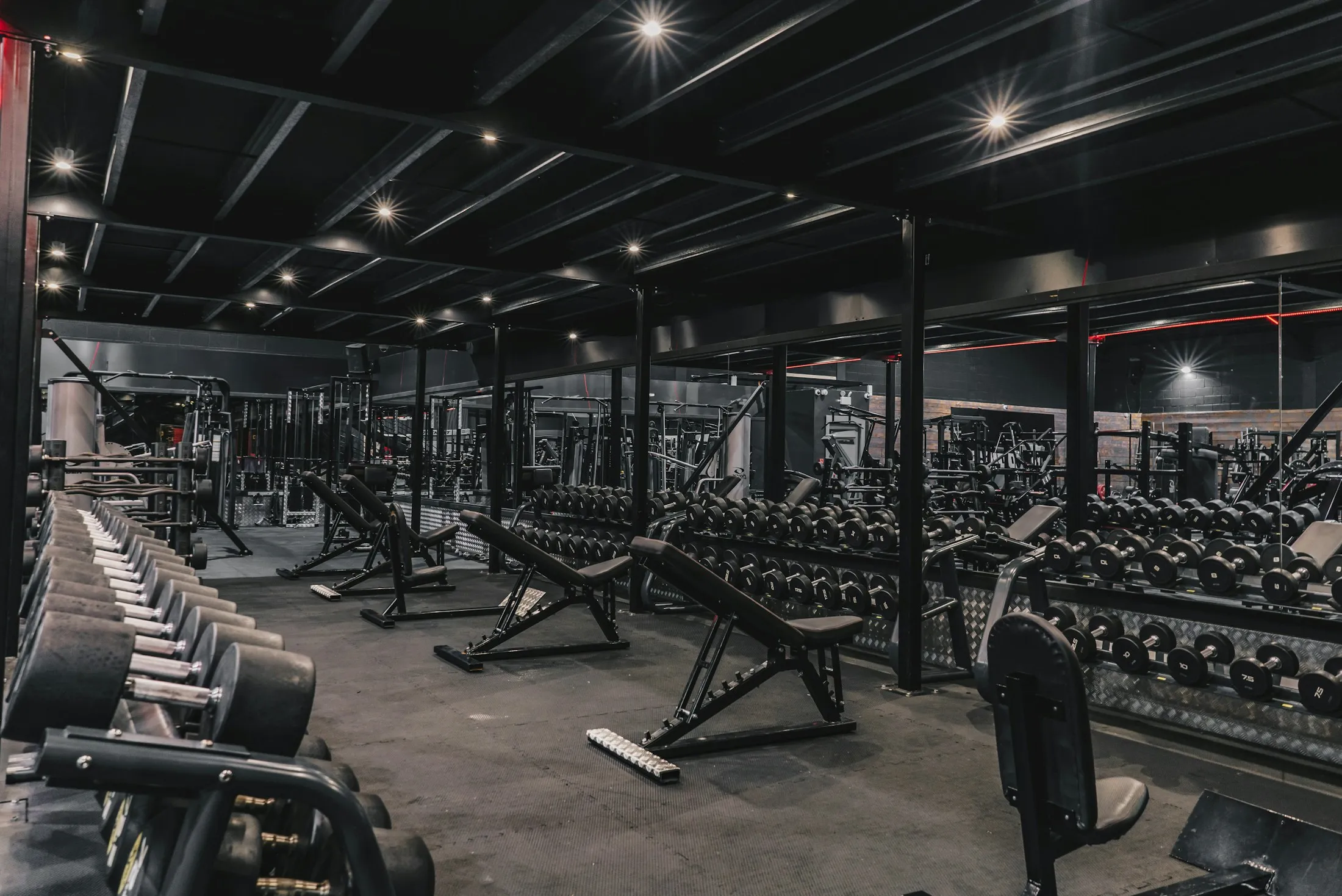 Ein modernes Fitnessstudio mit Hanteln und Trainingsbänken.