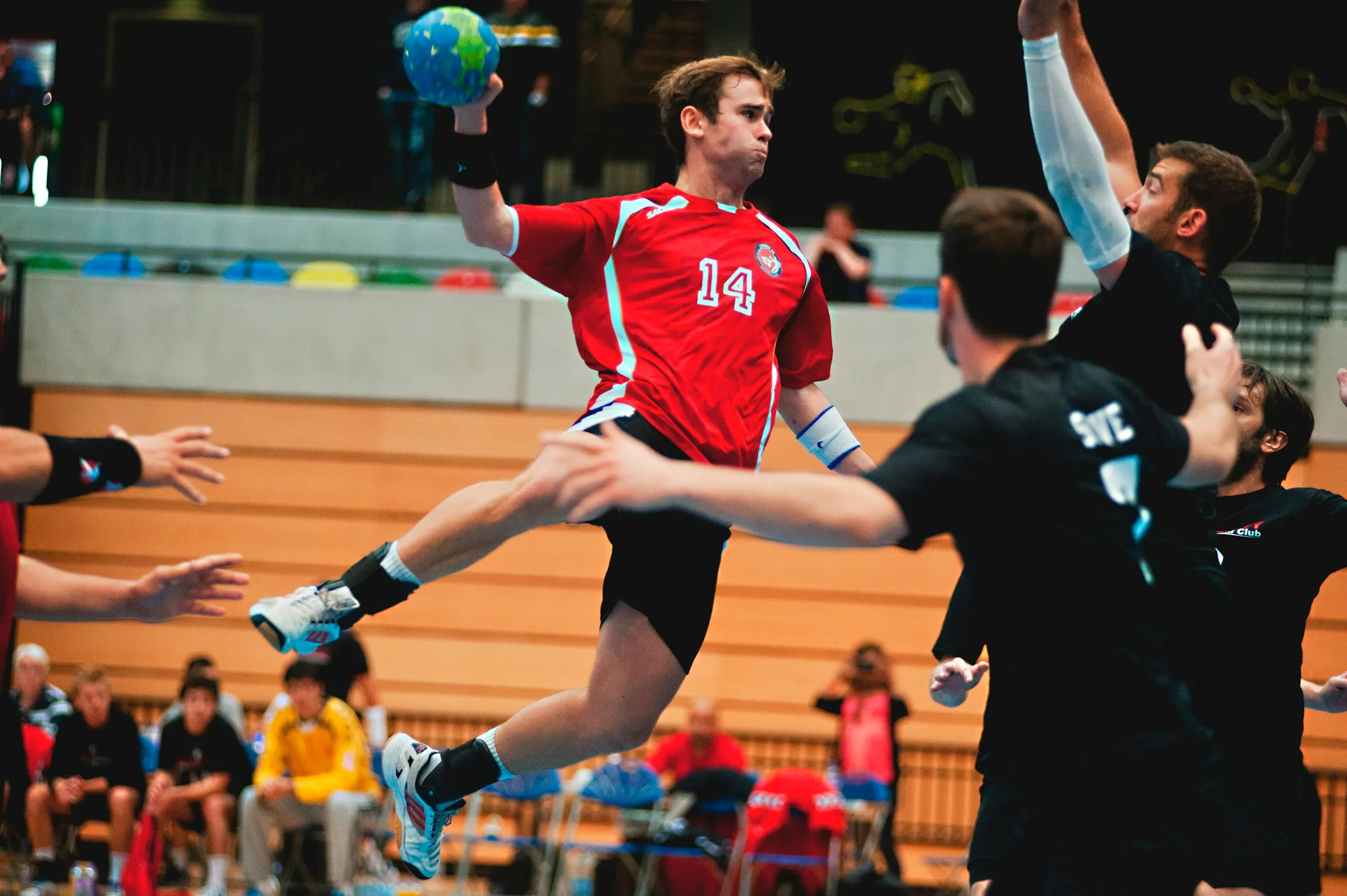 Ein Handballspieler springt beim Wurf vor der Abwehr hoch.
