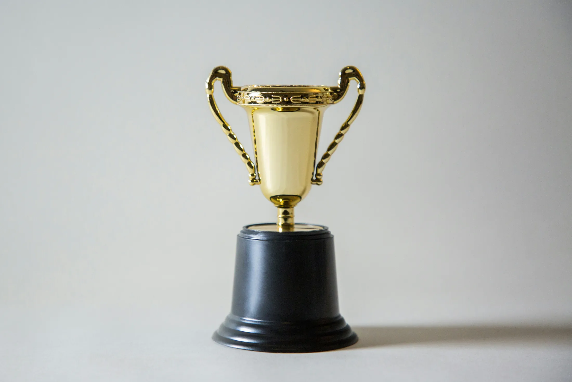 Ein goldener Pokal vor einem neutralen Hintergrund.