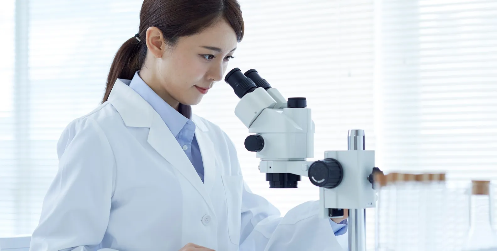 Eine Wissenschaftlerin arbeitet an einem Mikroskop.