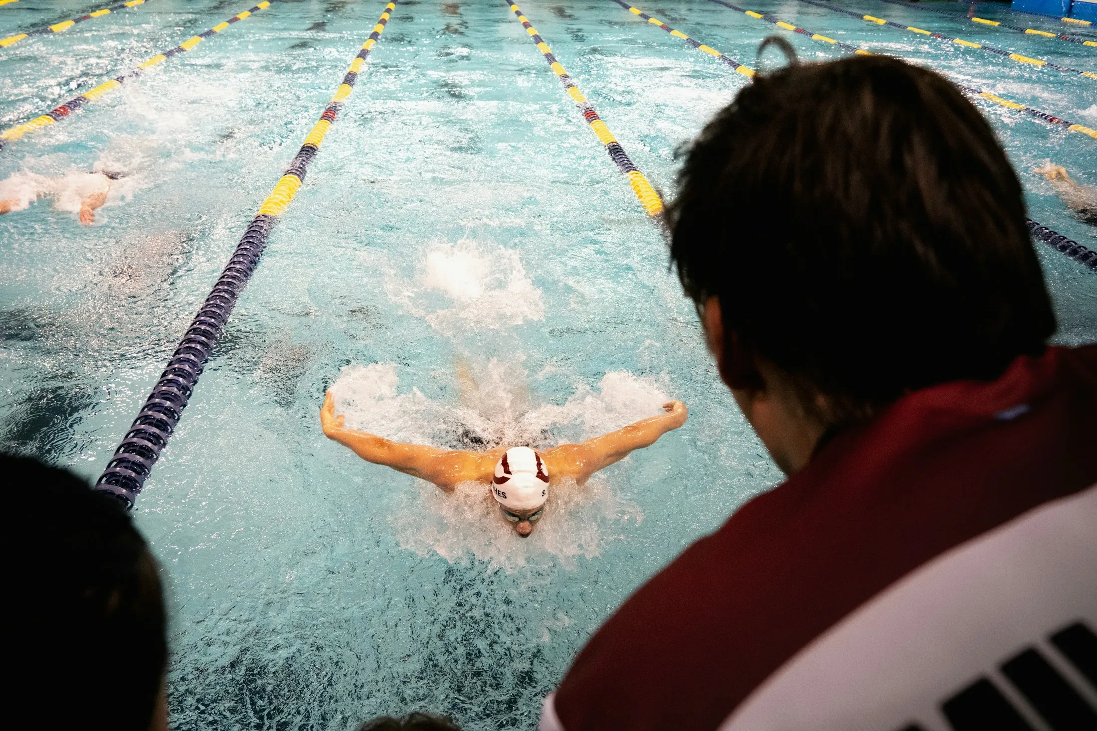 Eine Trainerin beobachtet einen Schwimmer auf der Bahn.