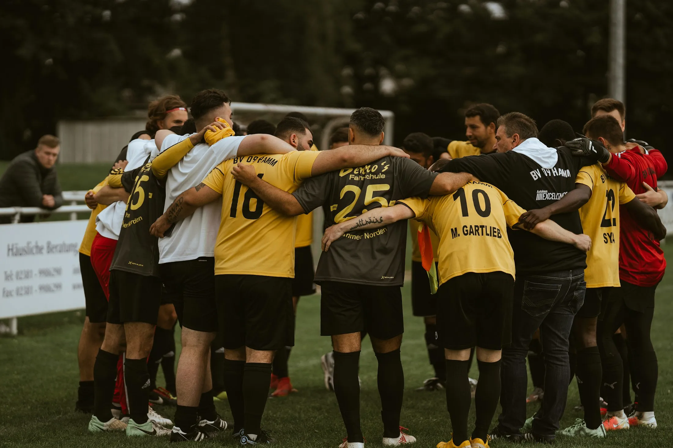 Eine Fußballmannschaft steht vor dem Spiel im Kreis zusammen.