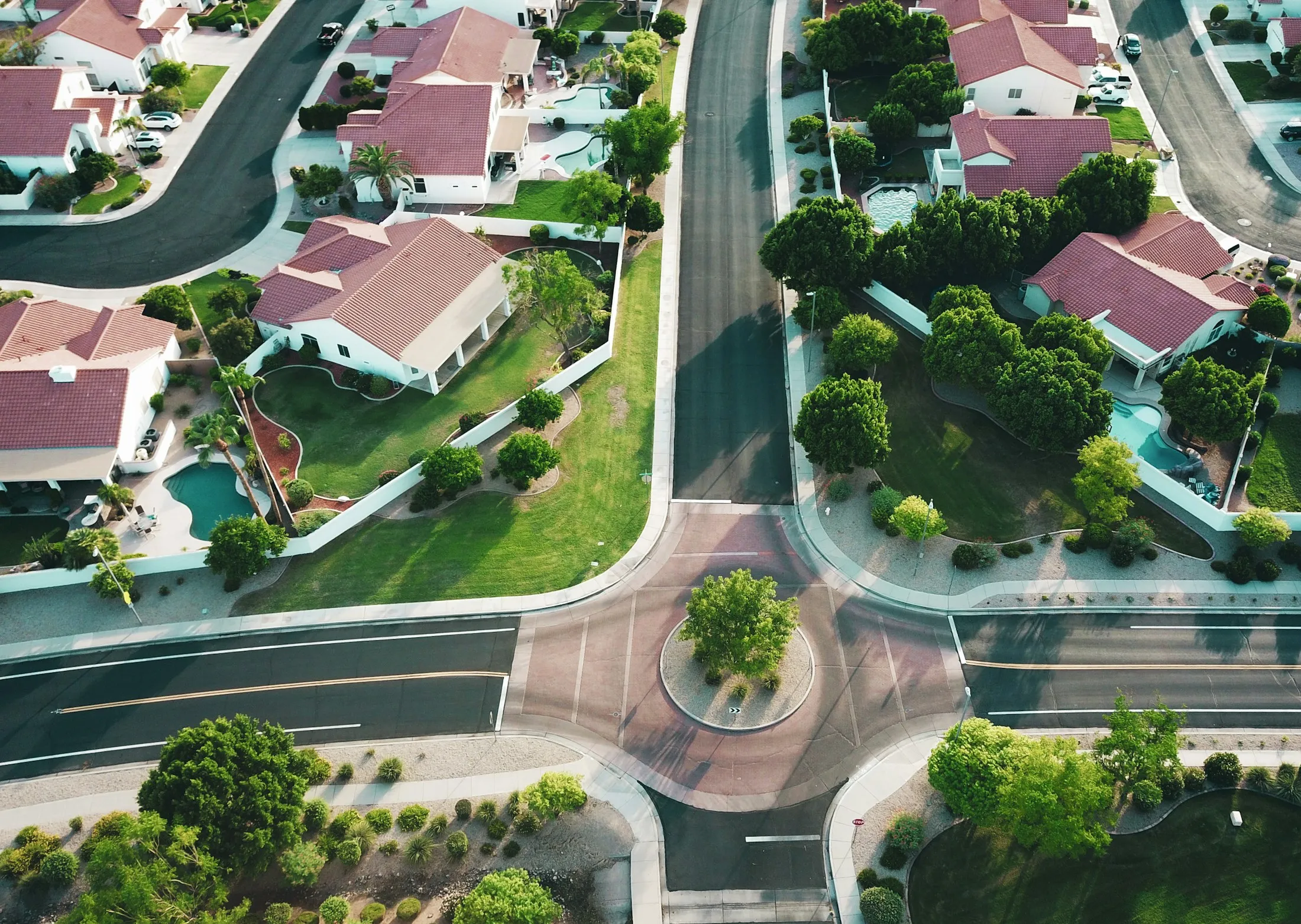 An aerial view of homes and streets around a neighborhood roundabout.