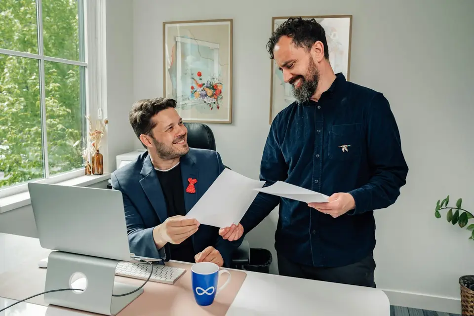 Zwei Männer arbeiten in einem hellen Büro gemeinsam an einem Schreibtisch